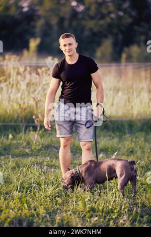 Amerikanischer Tyrannehund brütet mit einem etwa 20-jährigen europäischen Mann auf dem Land. Stockfoto