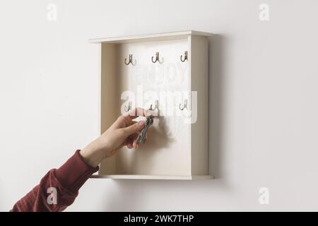 Die junge Frau hängt Schlüssel an den Schlüsselhalter an der Wand, Wohnkonzept Stockfoto