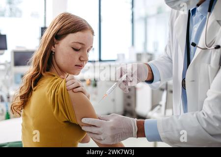 Arzt, Kinderarzt, der Impfstoff in den Arm eines Teenagers injiziert. Konzept der Gesundheitsvorsorge und Impfungen für Jugendliche. Stockfoto