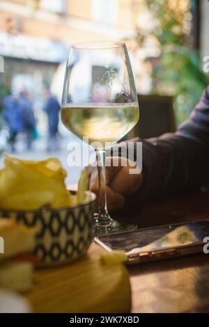 Eine Person sitzt an einem Tisch mit einem Glas Prosecco-Weißwein. Sie scheinen einen Moment der Entspannung, des Genusses zu genießen Stockfoto