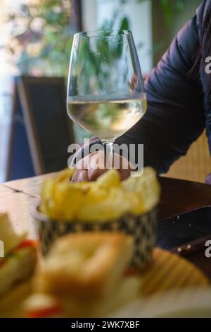 Eine Person sitzt an einem Tisch mit einem Glas Prosecco-Weißwein. Sie scheinen einen Moment der Entspannung, des Genusses zu genießen Stockfoto