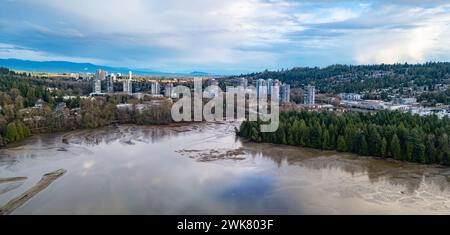 Die Gebäude der Stadt stehen hoch am Fluss unter einem bewölkten blauen Himmel Stockfoto