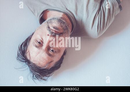 Hochklassiges Porträt eines depressiven Mannes, der im Bett liegt und in die Kamera blickt Stockfoto