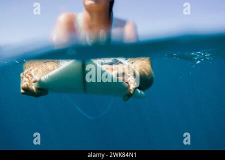 Unterwasseransicht Einer Surferin, die auf Eine Welle auf ihrem Surfbrett wartet Stockfoto