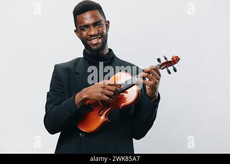 Leidenschaftlicher junger afroamerikanischer Mann, der sein Talent durch das Spielen der Geige demonstriert, isoliert auf weißem Hintergrund Stockfoto