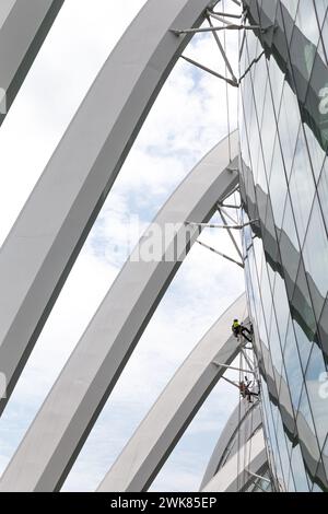 Zwei Fensterputzer, die an einem modernen, runden Glasgebäude arbeiten Stockfoto