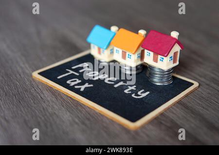 Spielzeughaus und Tafel mit Text GRUNDSTEUER. Immobilienkonzept. Stockfoto
