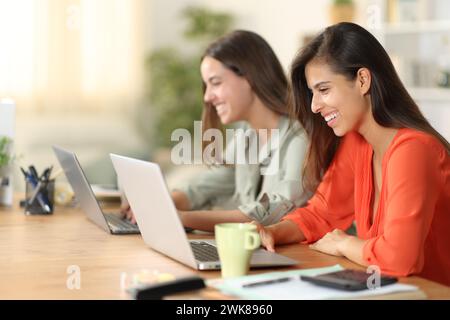 Zwei glückliche Tele-Mitarbeiter, die zu Hause online mit Laptops arbeiten Stockfoto