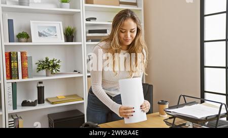 Porträt einer selbstbewussten, lächelnden jungen hispanischen Frau bei der Arbeit, einer schönen, erfolgreichen Geschäftsfrau, die Dokumente im Büro hält Stockfoto