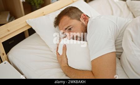 Besorgter Mann mittleren Alters mit grauen Haaren, der drinnen im Bett liegt und Angst oder Schlaflosigkeit darstellt Stockfoto