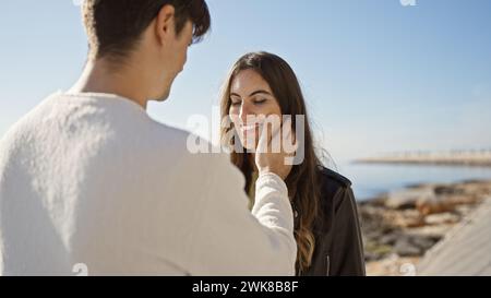 Ein liebevolles Paar genießt einen zärtlichen Moment am Meer und zeigt eine romantische Beziehung in einer wunderschönen Umgebung im Freien. Stockfoto