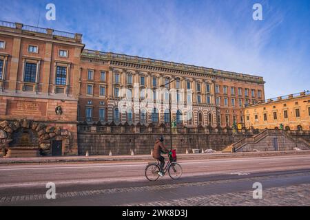 Eine Person, die vor dem Königspalast in Stockholm, Schweden, in der Altstadt radelt. Klarer Wintertag, Morgensonne. Stockfoto
