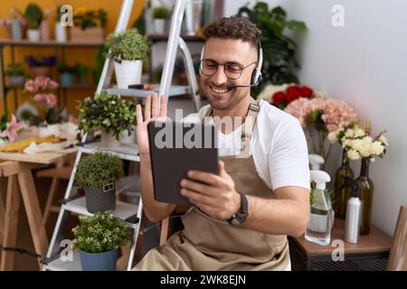 Hispanischer Mann mit Bart, der im Blumenladen arbeitet und ein Videogespräch führt. Er sieht positiv und glücklich aus und lächelt mit einem selbstbewussten Lächeln und zeigt Zähne Stockfoto