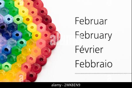 Der Kalendermonat Februar auf deutsch, englisch, französisch und italienisch - eine Regenbogendekoration Stockfoto