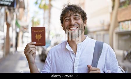 Hübscher bärtiger hispanischer Mann mit grünen Augen hält französischen Pass auf einer sonnigen Stadtstraße. Stockfoto