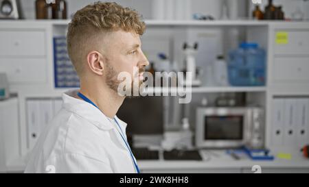 Kaukasischer Mann mit Bart und blauen Augen, der einen Labormantel in einem Labor trägt. Stockfoto