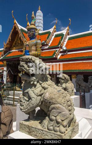 Ein Löwe und eine Yaksha-Statue im Tempel des Smaragd-Buddha-Komplexes auf dem Gelände des Grand Palace in Bangkok, Thailand. Stockfoto