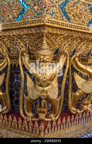 Goldene Statuen von Garuda vs. Naga bewachen den Tempel des Smaragdbuddhas im Grand Palace Complex in Bangkok, Thailand. Stockfoto