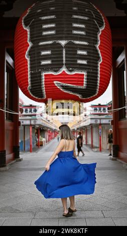 Die sprudelnde hispanische Frau tanzt fröhlich und dreht sich in wunderschönem Kleid inmitten der herrlichen Architektur des Senso-JI-Tempels in tokio. Sie ist durch japan gereist Stockfoto