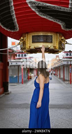 Fröhliche hispanische Frau in Brille, bezaubert von kolossalen asiatischen Laternen am Senso-JI-Tempel, schafft fantastische Reiseerinnerungen in tokios traditionellem Kuh Stockfoto