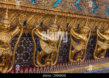 Goldene Statuen von Garuda vs. Naga bewachen den Tempel des Smaragdbuddhas im Grand Palace Complex in Bangkok, Thailand. Stockfoto