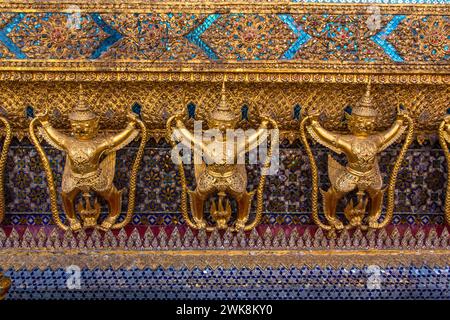 Goldene Statuen von Garuda vs. Naga bewachen den Tempel des Smaragdbuddhas im Grand Palace Complex in Bangkok, Thailand. Stockfoto