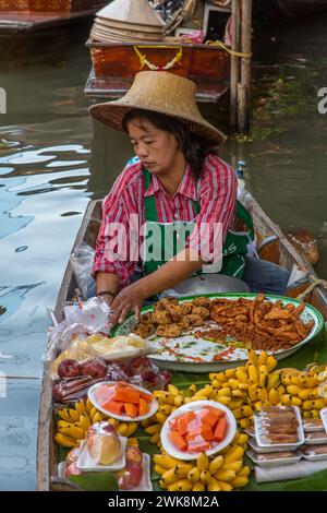 Eine Thailändin, die auf ihrem Boot auf dem schwimmenden Markt Damnoen Saduak in Thailand Essen zubereitete. Stockfoto