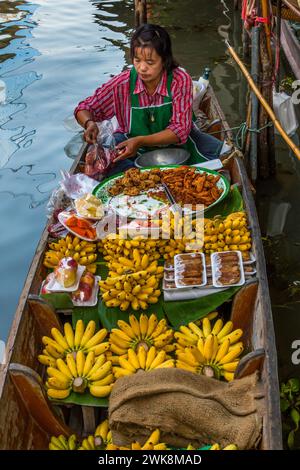Eine Thailändin, die auf ihrem Boot auf dem schwimmenden Markt Damnoen Saduak in Thailand Essen zubereitete. Stockfoto