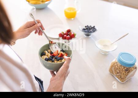 Eine Person bereitet eine gesunde Frühstücksschale mit frischem Obst und Joghurt zu Stockfoto