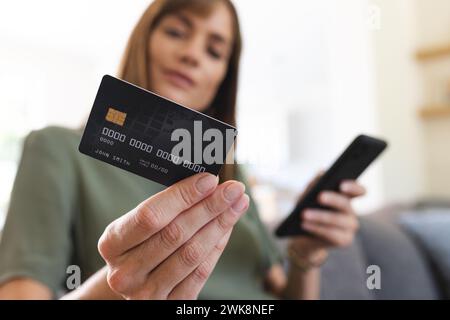 Die Frau verwaltet die Finanzen online mit Karte und Telefon und zahlt oder überprüft den Saldo. Stockfoto