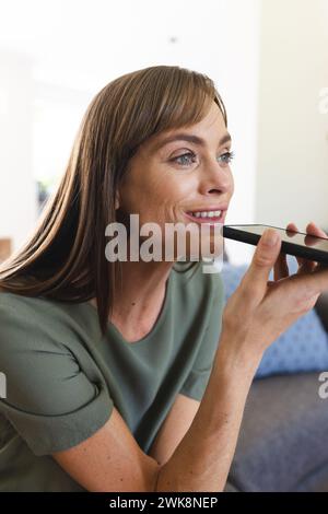 Eine weiße Frau mittleren Alters benutzt Sprachbefehle auf ihrem Smartphone Stockfoto