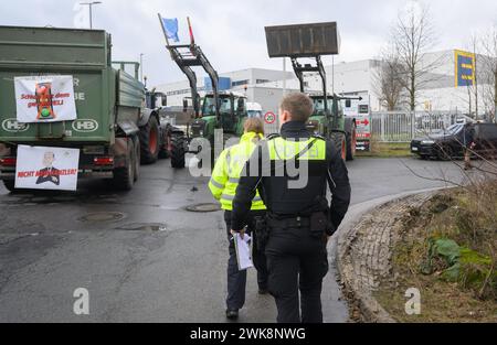 Lauenau, Deutschland. Februar 2024. Polizeibeamte stehen an einer Blockade mit Traktoren an einer Zufahrtsstraße zu einem Lager der Einzelhandelsfirma Edeka in der Nähe der Autobahn A2 im Stadtteil Schaumburg. Der Zugang zum und vom Standort sei nicht möglich, sagte eine Sprecherin der Polizeiwache Nienburg/Schaumburg. Fast 40 Fahrzeuge nahmen an der Blockade Teil. Quelle: Julian Stratenschulte/dpa/Alamy Live News Stockfoto