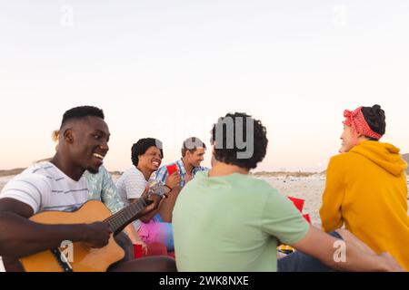 Verschiedene Freunde genießen Musik am Strand bei Sonnenuntergang, feiern eine Party, mit Kopierraum Stockfoto