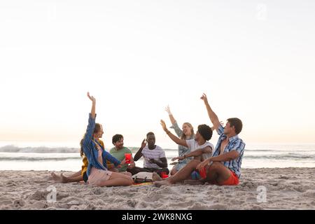 Verschiedene Gruppen von Freunden genießen einen Sonnenuntergang am Strand und feiern eine Party, mit Kopierraum Stockfoto