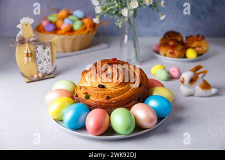 Craffin (Cruffin) mit Rosinen und kandierten Früchten. Traditionelles Osterbrot Kulich und bemalte Eier auf grauem Hintergrund. Osterferien. Nahaufnahme, se Stockfoto