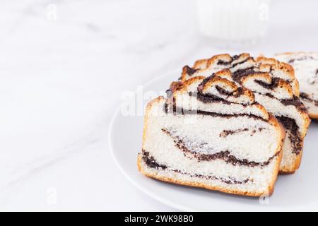 Frische süße leckere Hefe Backwaren mit Mohnfüllung auf weißer Platte auf weißem Hintergrund. Köstliches hausgemachtes Brötchen Stockfoto