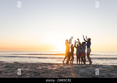 Verschiedene Freunde feiern am Strand bei Sonnenuntergang, mit Kopierraum Stockfoto