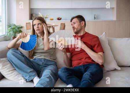 Überhitztes, irritiertes Ehepaar, das zuwinkend müde ist, erliegt unerbittlicher Hitze zu Hause Stockfoto