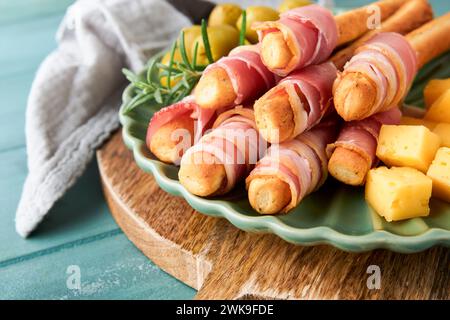 Schinkenscheiben oder Marmeladen. Köstliche grissini-Sticks mit Schinken, Käse, Rosmarin, Oliven auf grüner Platte auf dunklem Hintergrund. Vorspeisentisch Stockfoto