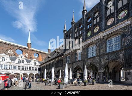 Lübeck, 17. April 2023: Marktplatz umgeben von Lübecker Rathausbauten in verschiedenen Architekturstilen, Stadtleben mit Straßencafé und Stockfoto