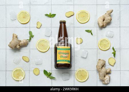 Komposition mit einer Flasche frischen Ingwerbiers, Minze, Zitronenscheiben und Eiswürfeln auf hellem Fliesenhintergrund Stockfoto