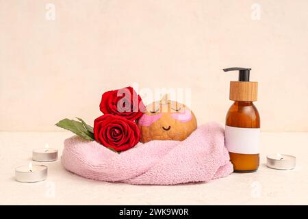 Kürbis mit gezeichnetem Gesicht, Flecken unter den Augen, Spa-Zubehör und Rosen auf hellem Hintergrund Stockfoto