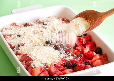 Eine Crumble-Mischung wird über gedünsteten, weichen Apfel und Brombeeren gestreut, um eine brombeere und Apfelbrösel zu machen. Eine traditionelle englische Wüste Stockfoto