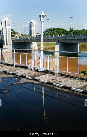 Die Reflexion eines altmodischen Straßenlaternenpfosten in einer Regenpfütze auf einer alten Brücke Stockfoto