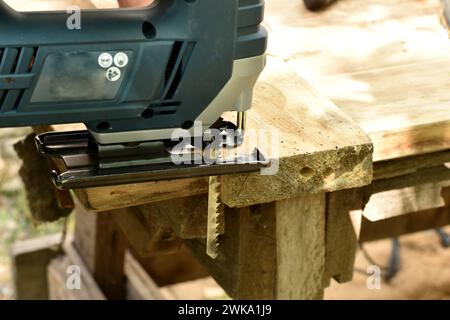 Stichsäge mit Elektrowerkzeug schneidet ein Stück von der Platine ab, Seitenansicht. Stockfoto