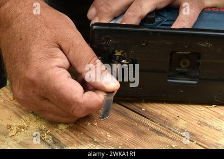 Der Zimmermann bereitet ein Elektrowerkzeug für die Arbeit vor, er steckt eine Säge hinein. Stockfoto