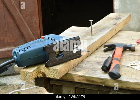 Nahaufnahme eines Zimmermannsarbeitsplatzes, eine Stichsäge, ein Hammer, ein Schraubenzieher liegen auf dem Tisch. Stockfoto