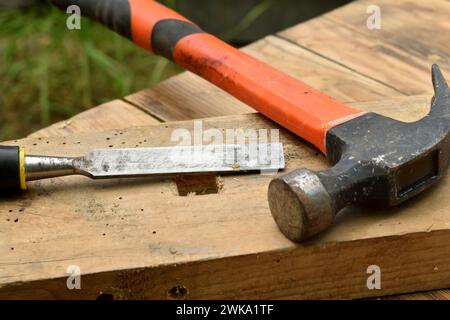 Auf dem Brett sind ein Meißel und ein Hammer, ein Zimmermannswerkzeug. Stockfoto