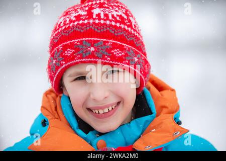 Nahporträt eines Jungen mit rotem Winterhut. Kind im Winter. Stockfoto