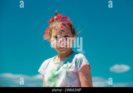 Kinder Holi Festival der Farben. Bemaltes Gesicht eines lächelnden Kindes. Kleines Mädchen spielt mit Farben. Stockfoto